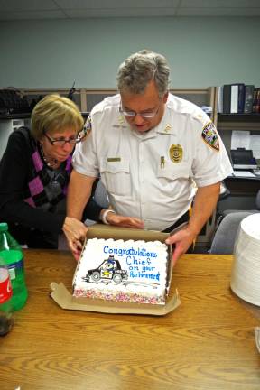 Photo by Chris Wyman Jeanne Buffalino, the Vernon PAL Director, adjusts the cake for retiring Vernon Township Police Chief Roy Wherry. There was an informal luncheon held for him last Thursday in the Vernon Police Department offices.