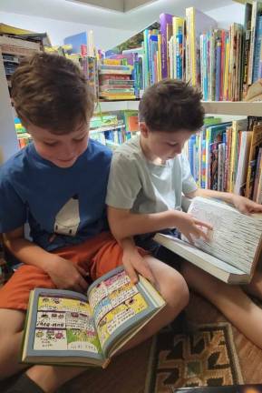 Rowan and Isaac Martens reading at home in Minisink, N.Y. The Martens were first in their town to sign up for a Port Jervis, N.Y., library card, but because it’s a 19-minute drive, they rarely get there. Now, with newly limited access, it becomes still less convenient, but the Martens plan to make the effort to go this summer. “I want my kids to have the library experience,” Melissa Martens said, “even if it’s not convenien.” Photo by Melissa Martens.