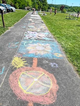 Chalk drawings are lined up on the pavement at Maple Grange Park in Vernon.