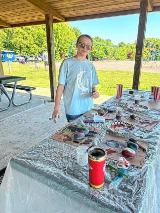 Mia Islami, 11, paints rocks in the pavilion.