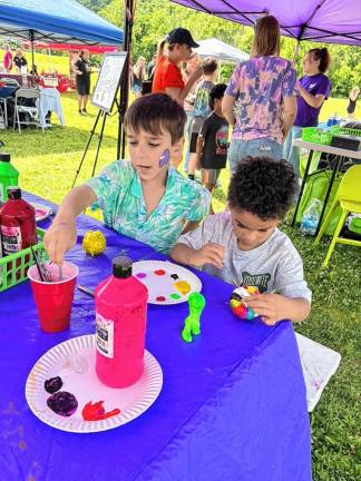 Caden Reines, 8, and Nathan Isaac, 7, paint ceramics in the Painted Grape tent.