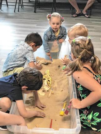 <b>Children dig to uncover dinosaur fossils.</b>