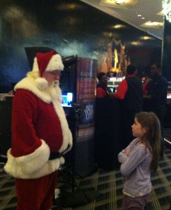 Submitted by: Eileen Phillips of Goshen, N.Y. &quot;After visiting Santa at Macy's Herald Square, we took my 9 year old niece to The Radio City Christmas Show. Sophia questioned whether this was the same Santa that she saw earlier, in this picture she's asking him if he remembered what she told him earlier what she wanted for Christmas.&quot;