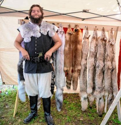 Kyle Marx stands in front of animal pelts.