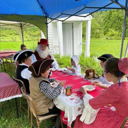 John Bradford, dressed as Santa Claus, has an ice cream sundae with young visitors outside the Rev. Elias Van Bunschooten Museum in Wantage.