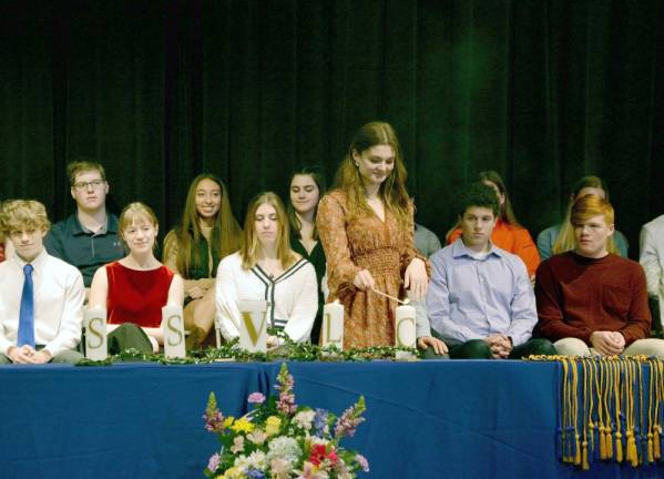 Vernon Township High School National Honor Society secretary Gabrielle Miller lights a candle during the induction ceremony.