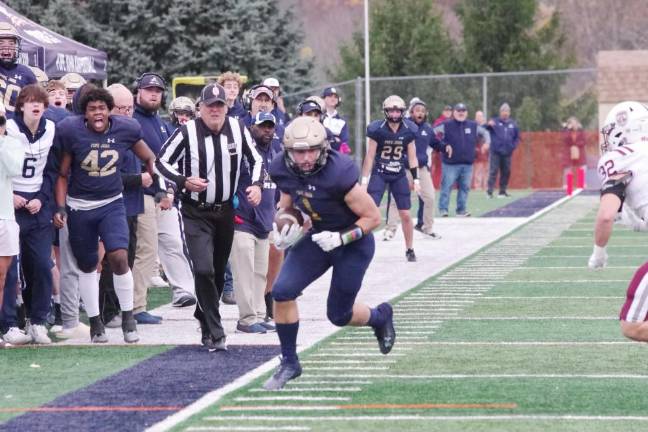 Pope John ball carrier Joseph Walton runs along the sideline as his team cheers him on.