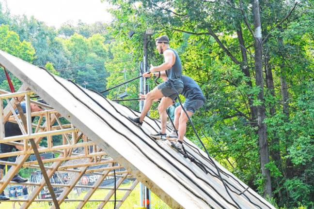 <b>Spartan Race competitors climb a Slip Wall using ropes.</b>