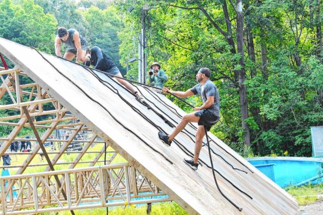 <b>Spartan Race competitors climb a Slip Wall using ropes.</b>