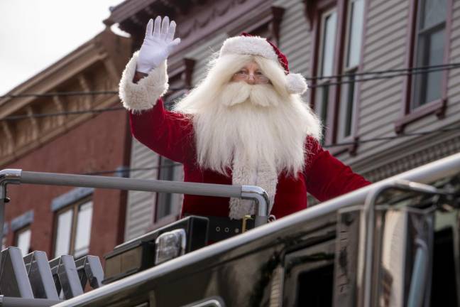 Santa Claus rides on a firetruck in the parade.