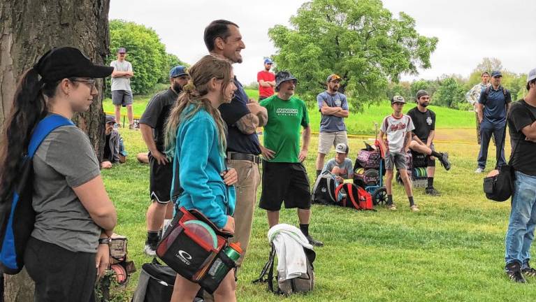 <b>Participants in the disc golf tournament listen to instructions.</b>